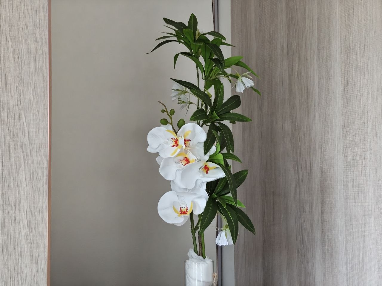 White orchids against leather-textured wall panels and rose gold trim